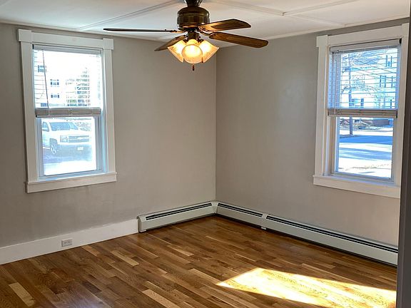 Large living room with pull down blinds and ceiling fan.