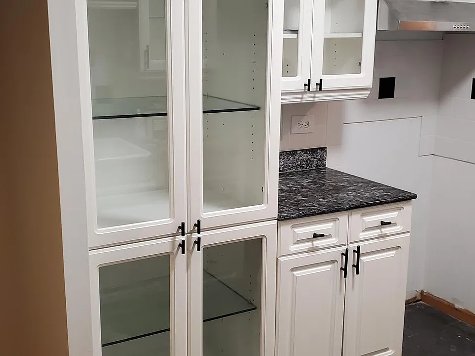 Glass front white cabinets, with glass shelves. Granite countertops and mable floors. French Provencal themed