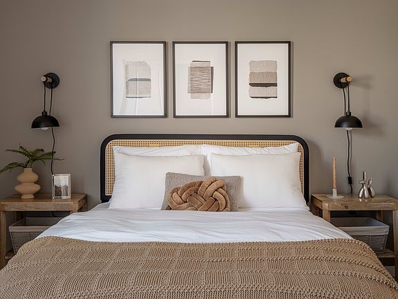 A cozy and minimalist bedroom with a white bed, wooden nightstands, and framed abstract art on the w