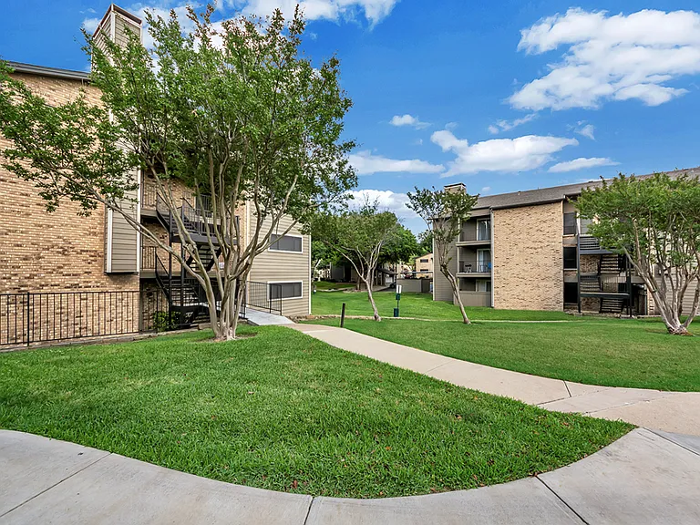 Exterior apartment buildings with mature trees and landscaped grounds