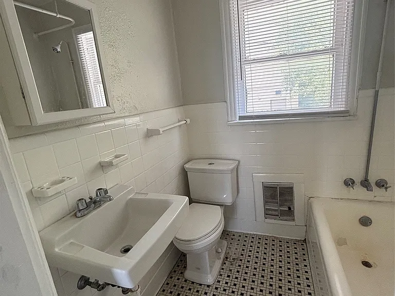 Bathroom featuring white ceramic wall tile, patterned floor tile, a pedestal sink, and a window with blinds
