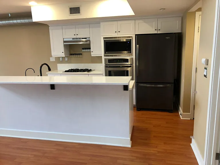 new white quarts counter top, new sleek appliances, sink, white kitchen cabinets, and washer dryer