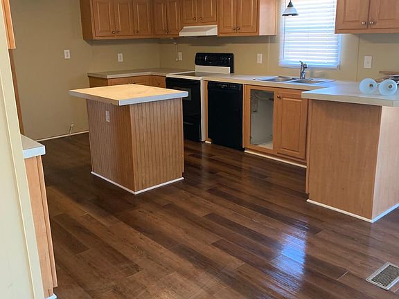 Kitchen with new flooring and refrigerator being installed.