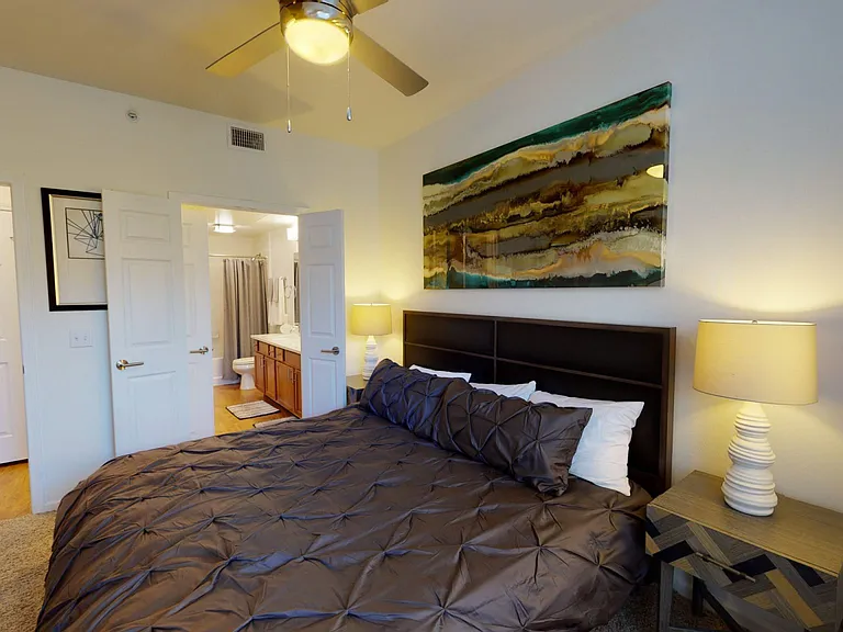 Spacious apartment bedroom with attached bathroom and plush carpet flooring.