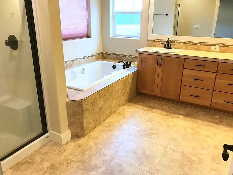 Main bathroom (attached) with dual sinks, bath tub ,shower cabin with lots of storage