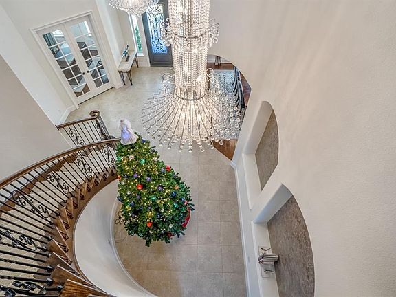 The dramatic spiral staircase, and family of custom chandeliers, art niches, open concept living make this home desirable.