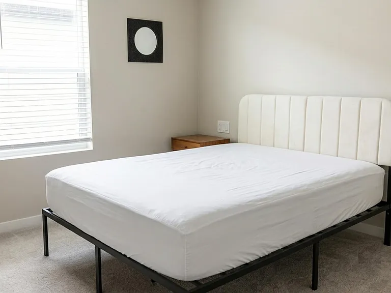 Private bedroom with a comfortable bed, neutral walls, and a window with blinds for adjustable natural light.