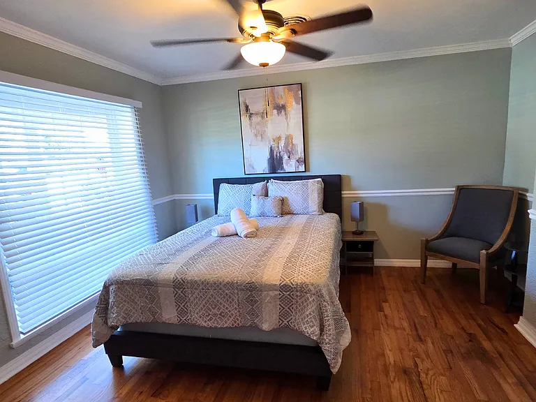 Bright bedroom with large window, beautiful blinds, and wall art