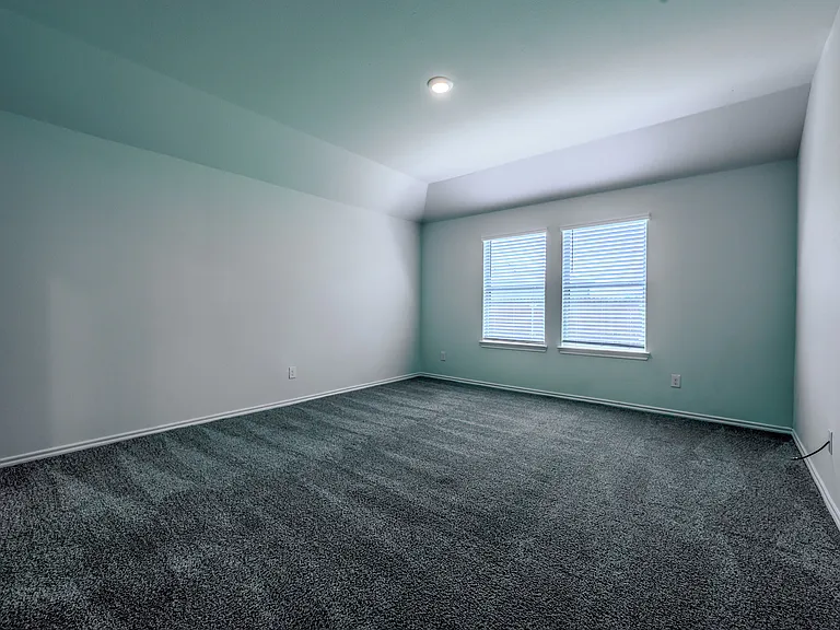 Large primary bedroom with double windows overlooking the backyard