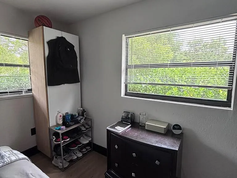 Bedroom with two windows, dark wood flooring, and space for a bed plus dresser and wardrobe storage.