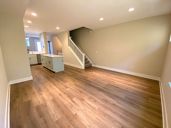 Open-concept kitchen & living area with Bosch appliances, quartz countertops, custom backsplash, and breakfast bar cafe.