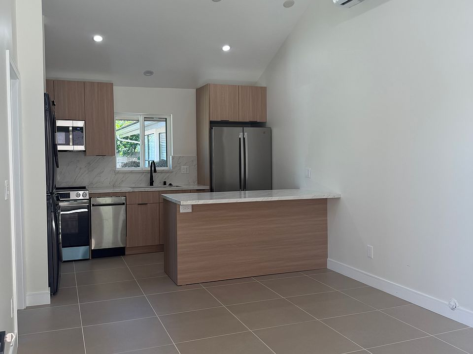 View from the front door. Open floorplan. Modern kitchen, island, full size refrigerator, washer, and dryer.