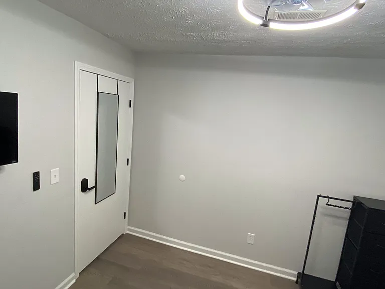 Private room with durable flooring, a ceiling fan/light, and convenient wall outlets near the entry door.
