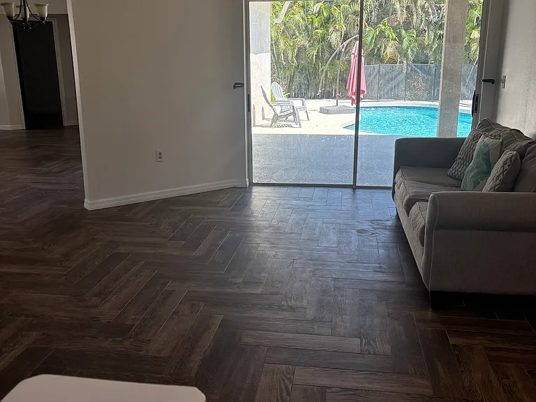 Inside living room and dining room area with entire view of swimming pool and palms completely fenced backyard