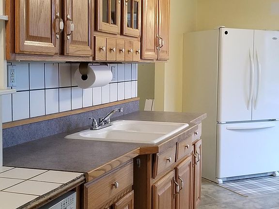 New corner refrigerator, entrance to media room, lighted china cabinet over sink, tiled backsplash, under cabinet tilt-lights, 18" tile top dishwasher with built in canister shelving up to ceiling.