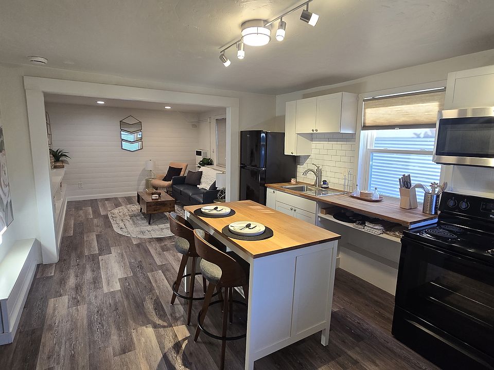 ChatGPT said:

Open-concept kitchen flowing into a furnished living area, with island seating, full-size appliances, and warm, modern finishes throughout.