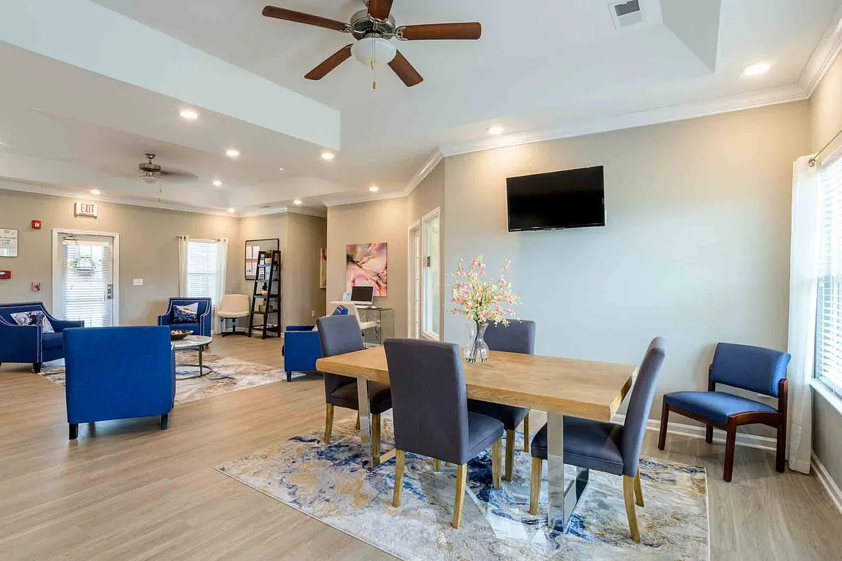 Spacious community lounge with ample seating, wall-mounted TV, and natural lighting, perfect for meetings or resident events at Cedar Terrace Apartments. - Cedar Terrace