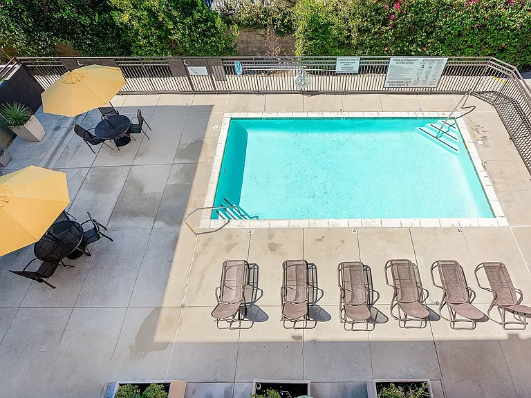 Private Pool Area with Lounge Chairs and Patio Tables with Umbrellas