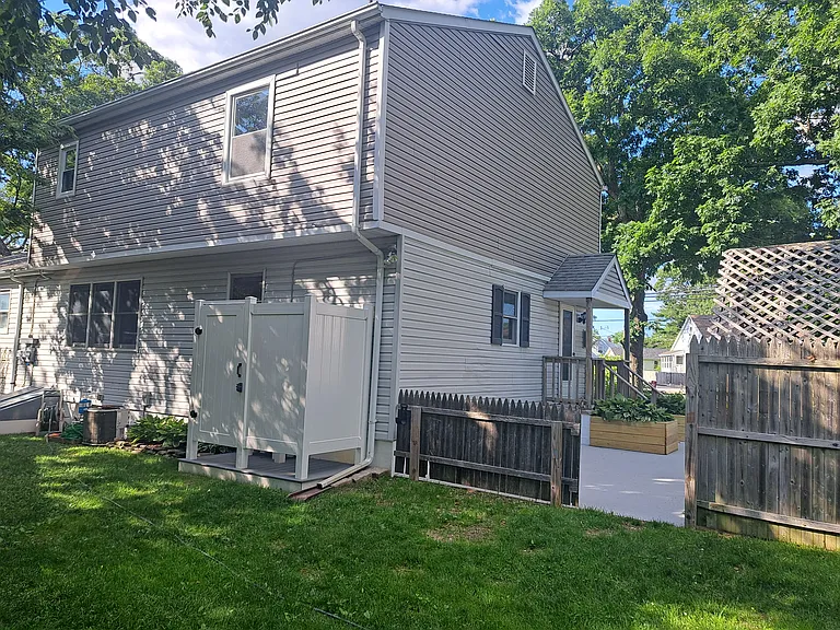 View of patio and outdoor shower from rear yard