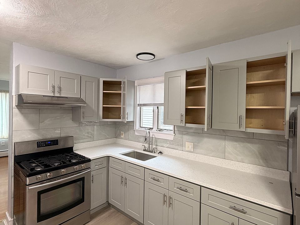Newly-renovated kitchen with new refrigerator, range-top stove, and ample cabinet storage space.