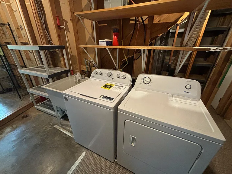 Large washer and dryer with handy utility sink to the left and storage shelves galore.