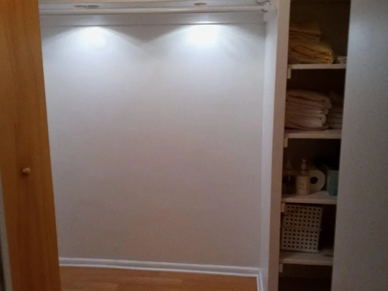 Hall closet with shelving, ample storage and lighting.