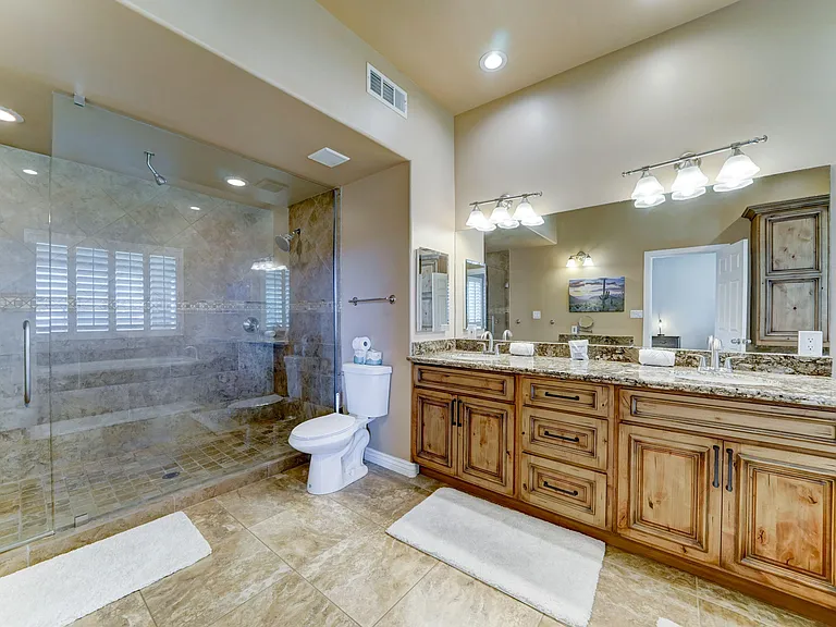Spacious bathroom with a dual-sink vanity, ample counter space, and a glass-enclosed walk-in shower with tile surround.