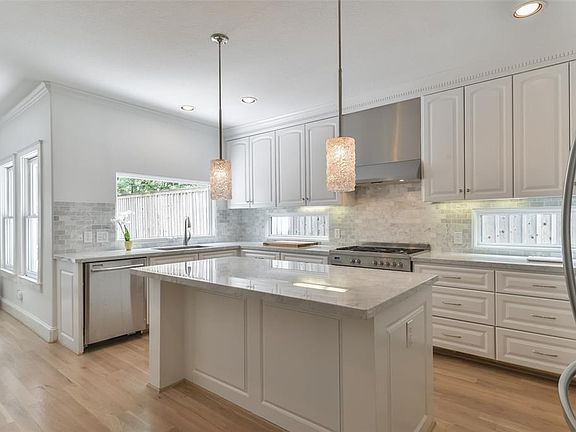 Another view of this pristine kitchen with windows overlooking decked patio.  Notice the clean lines, hardware on cabinetry and natural light.