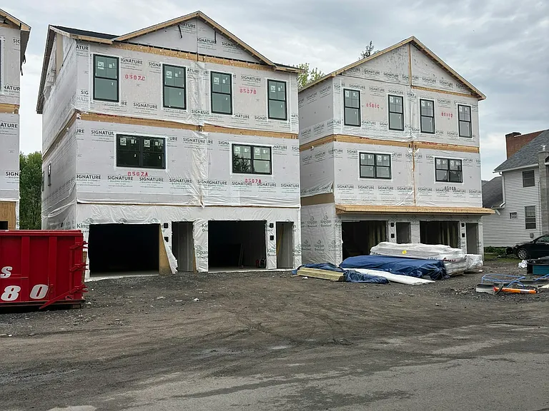 Exterior, White siding and black garage doors coming