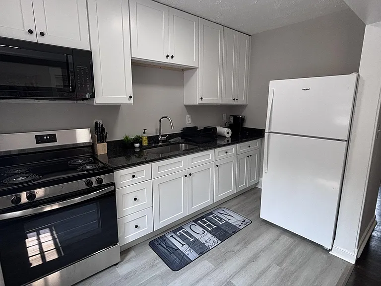 Kitchen offers ample white cabinetry, generous counter space, and a full appliance set including range, microwave, and refrig