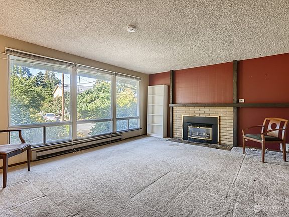 The spacious upper level of home features a formal living area with fireplace and large windows overlooking the front yard.>