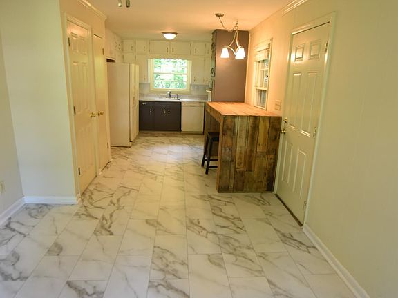 Breakfast area into kitchen with NEW floors! Wood desk inside of the carport door.