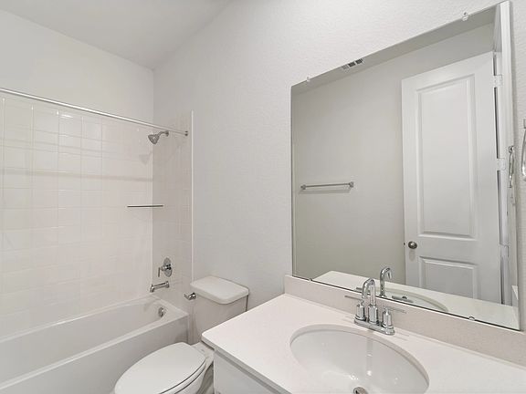 The second bath features tile flooring, white cabinetry and light countertops and a shower tub combo