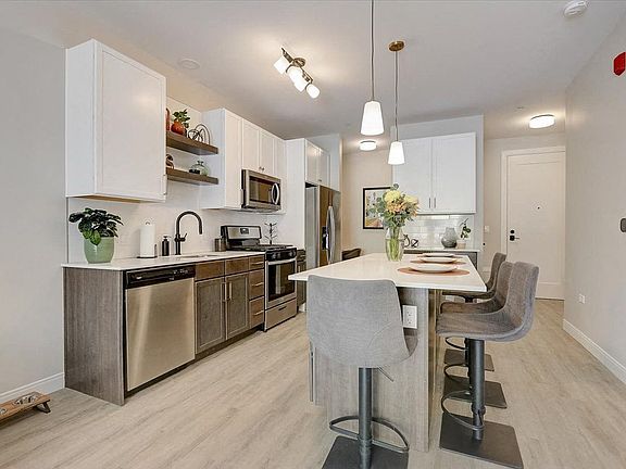Kitchen with island, stainless steel whirlpool appliances, quartz countertops, floating shelves and two tone cabinets