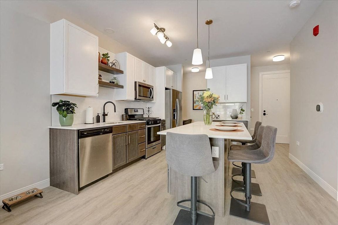 Kitchen with island, stainless steel whirlpool appliances, quartz countertops, floating shelves and two tone cabinets
