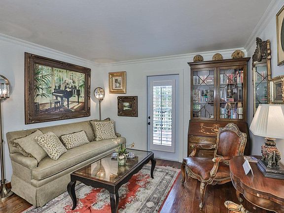 Comfortable living room with silk rug, Hardin sofa, oil paintings, glass protected designer coffee table, and 2 dimmable floor lamps