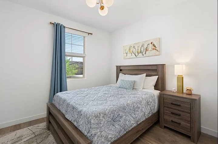 Cozy queen bedroom with soft linens, blinds, and blackout curtains for a comfortable night's sleep.