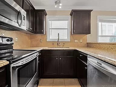 Kitchen with granite countertops, SS appliances with modern lighting throughout and tile flooring.