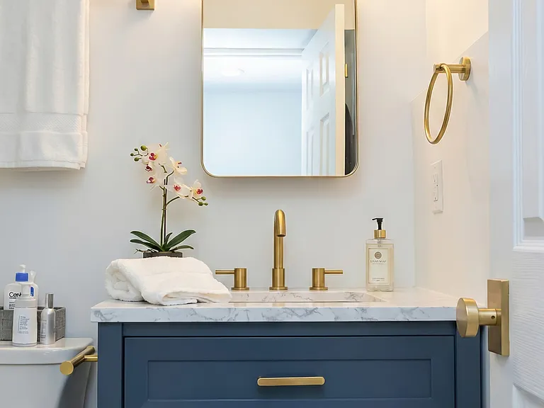 Updated bathroom vanity with blue cabinetry, gold-toned hardware, and modern mirror.