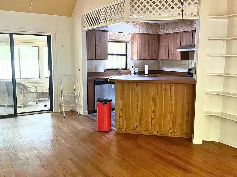 Living room includes built-in shelves and opens up to kitchen