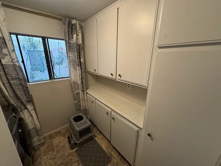 Laundry room feature cabinets and externally facing window.