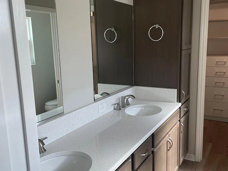 Primary bath with double sinks and quartz. Glimpse of the closet and there is a private door to the toilet.