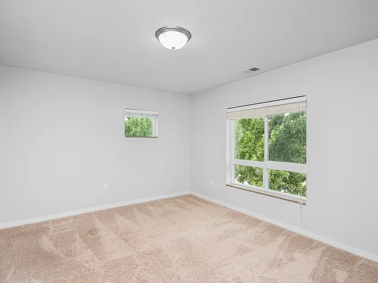 Bright and airy bedroom with plush carpet and large windows overlooking greenery. Bright and airy bedroom with plush carpet and large windows overlooking greenery.