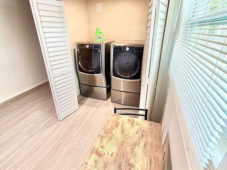 Convenient laundry nook with side-by-side washer and dryer, plus nearby counter space and natural light from the window.