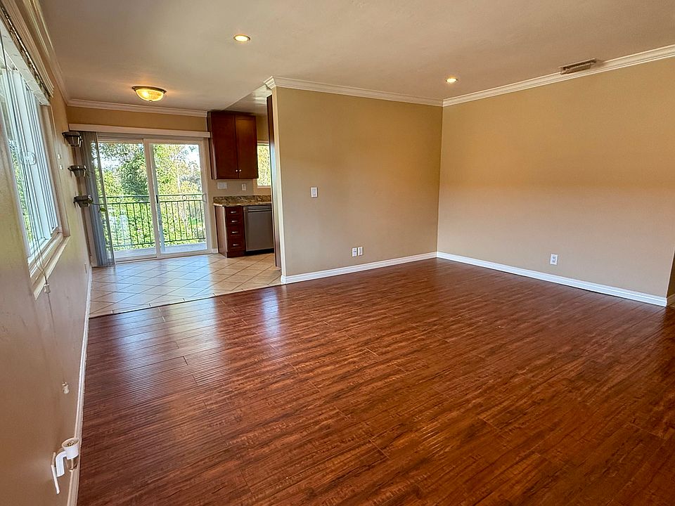 Spacious living room that flows into a dining area and kitchen with tree-lined views.