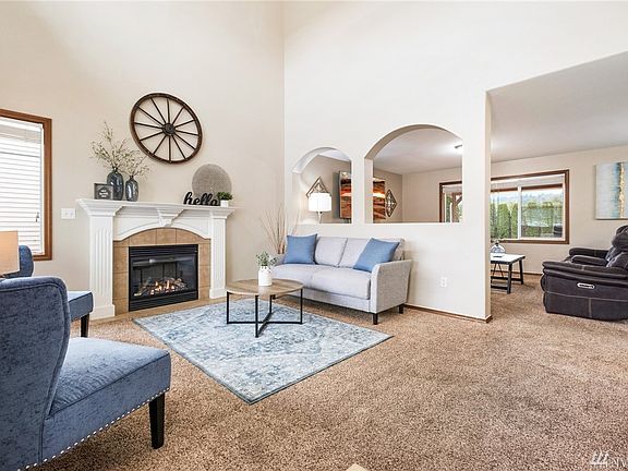 Enter into the living room with gas fireplace. LOADS of natural light in this room with tons of windows and cathedral ceiling with ceiling fan. 