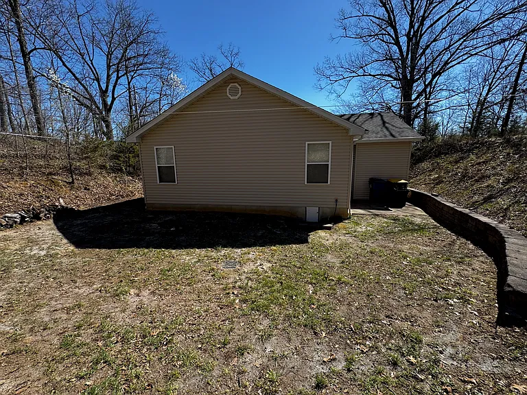Back side of house with a concrete patio on the side - perfect for get togethers and small fires. Plenty of wood for your convenience.