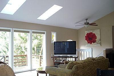 Living room with large windows, skylights and ceiling fan.