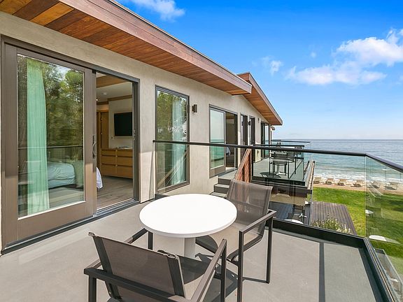 Private outdoor balcony with dining chairs and table.