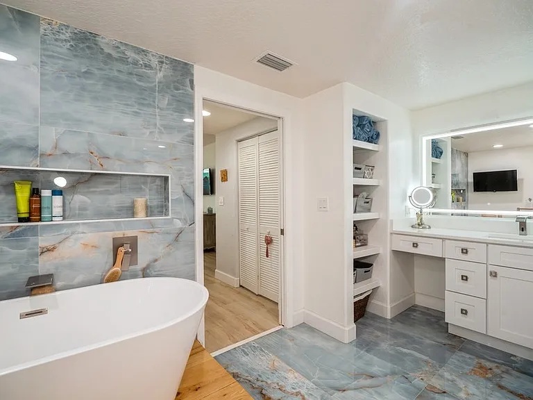Primary bathroom offers a soaker tub with TV, separate shower, private toilet area and makeup vanity